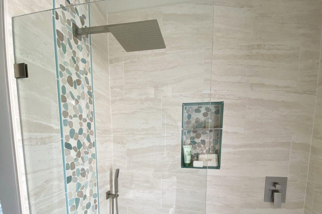 Shower Niches: Why you should get rid of that bulky shower rack! 11 Beachy Shower with Pebbles scaled e1760542392522