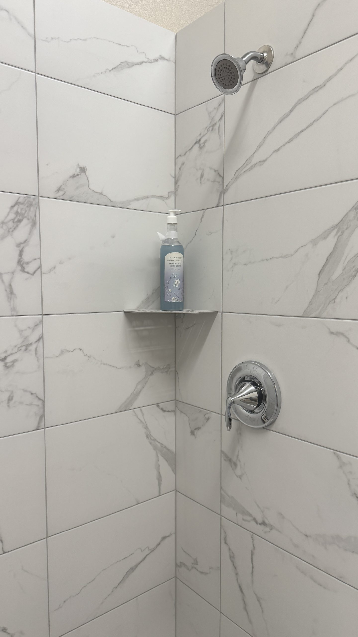 Marble-look tiled shower with coordinated floor and trim